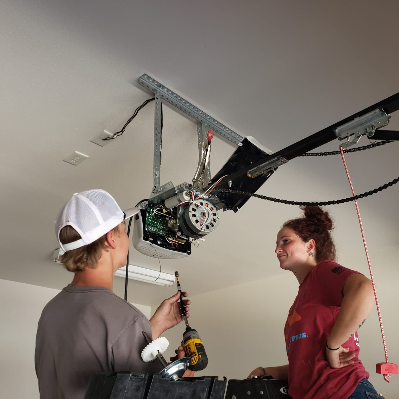 A garage door technician working on an installed opener, the kind of annual tune-up work that prevents the calls nobody wants to make in January.