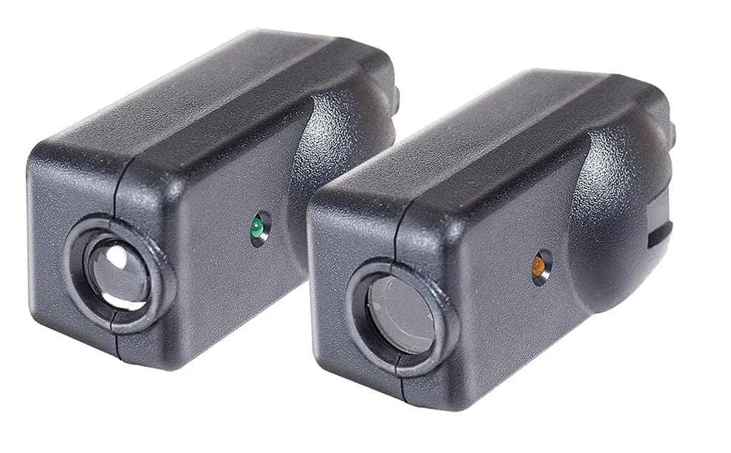 A pair of black garage door photo-eye safety sensors with LED indicator lights.